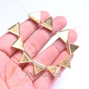 以下が含まれることがあります： 銀色のスペーサーが付いた、金色調の三角形のビーズのストランド。ビーズは半透明で、キラキラとした仕上がりです。