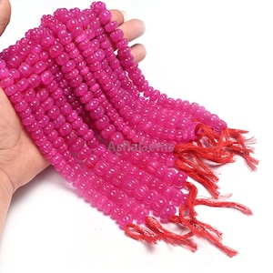 Op de afbeelding: Een streng roze edelsteen kralen, met een geknoopte kwast aan het einde. De kralen zijn rond en hebben een licht hobbelige textuur.