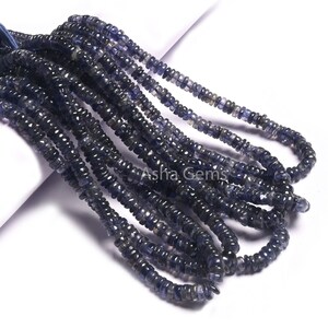 Peut inclure: Un brin de perles de pierres précieuses bleues, probablement du kyanite, de forme légèrement irrégulière et facettées. Les perles sont enfilées sur un fil transparent et disposées en un motif lâche et fluide.