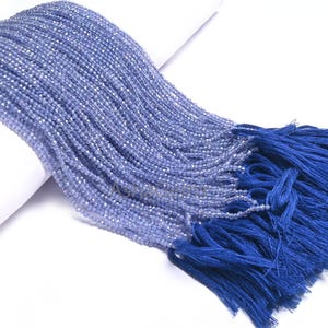 Puede incluir: Una hebra de cuentas de piedras preciosas de color azul claro con un borla azul. Las cuentas son peque&ntilde;as y redondas, y la borla est&aacute; hecha de un material suave y sedoso.