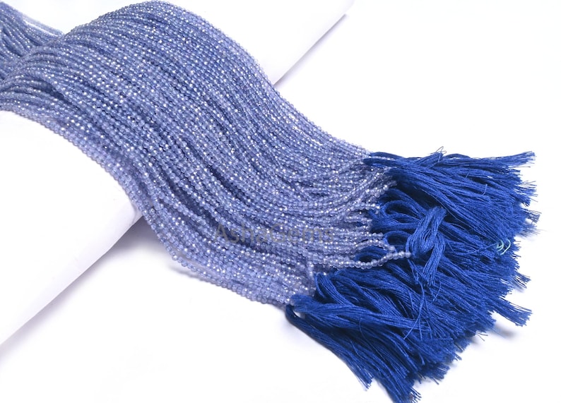 Puede incluir: Una hebra de cuentas de piedras preciosas de color azul claro con un borla azul. Las cuentas son peque&ntilde;as y redondas, y la borla est&aacute; hecha de un material suave y sedoso.