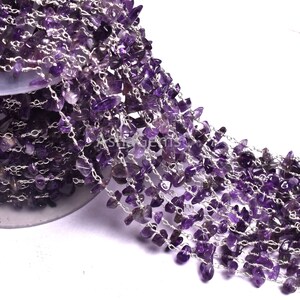 Puede incluir: Una hebra de chips de piedra preciosa de amatista enhebradas en una cadena de plata. Las virutas son de color morado oscuro y de diferentes tamaños. La cadena es delicada y tiene un brillo sutil.