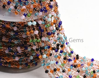 May include: A spool of copper chain with assorted colored glass beads, including blue, green, pink, orange, and black. The chain is wound around a clear plastic spool.