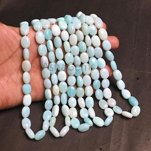 May include: A collection of smooth, oval-shaped light blue and white gemstone beads arranged in multiple vertical strands. The beads exhibit a polished, opaque finish with subtle color variations, creating a uniform appearance across the strands.