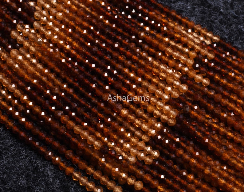 May include: A strand of brown and orange gemstone beads. The beads are faceted and have a shiny finish. The beads are arranged in a diagonal pattern.