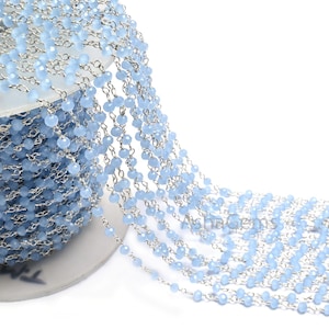 Könnte beinhalten: Eine Spule mit hellblauen Edelsteinperlen, die auf einer silbernen Kette aufgefädelt sind. Die Perlen sind facettiert und haben einen dezenten Schimmer.