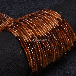 May include: A strand of brown and orange gemstone beads. The beads are faceted and have a shiny finish. The beads are strung on a clear thread and are ready to be used for jewellery making.