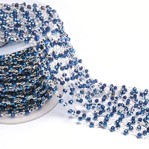 May include: A spool of silver chain with dark blue faceted beads. The chain is made of metal and the beads are made of glass.