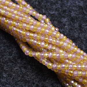 May include: A strand of pink and yellow faceted glass beads. The beads are small and round, and they are strung together on a clear thread.