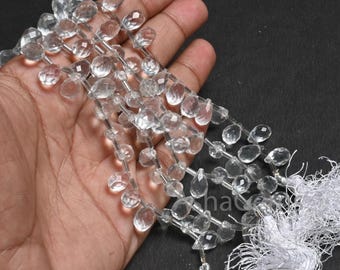 May include: A strand of clear quartz faceted beads, each bead is a teardrop shape. The beads are strung on a silver wire and have a white tassel at the end.