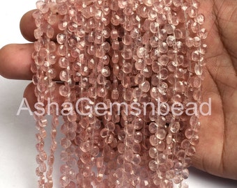 May include: A strand of light pink rose quartz beads. The beads are faceted and have a slightly irregular shape. The beads are strung on a clear elastic cord.