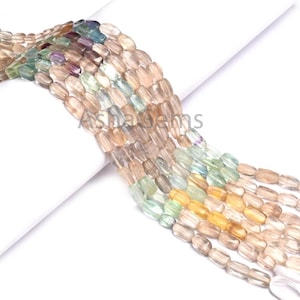 May include: Strands of colorful, oval-shaped beads in shades of yellow, green, purple, and brown. The beads are strung together, creating a flowing, textured appearance. The beads are likely used for jewelry making.