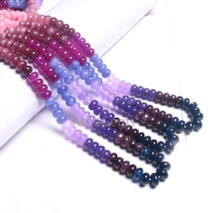 Puede incluir: Una hebra de cuentas de piedras preciosas en tonos rosa, morado y azul. Las cuentas son redondas y tienen un acabado liso y pulido.