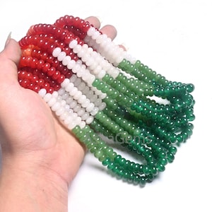 Puede incluir: Una hebra de cuentas de piedras preciosas rojas, blancas y verdes. Las cuentas son redondas y tienen un acabado liso y pulido.