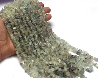 May include: A strand of green, blue, and purple fluorite chip beads. The beads are irregular in shape and have a natural, rough texture.  Asha Gems.