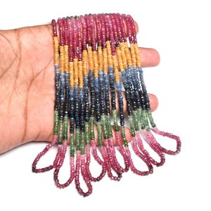 Pode incluir: Fios de contas coloridas de pedras preciosas em tons de rosa, vermelho, amarelo, azul e verde. As pequenas contas facetadas são enfiadas para criar um colar ou pulseira.