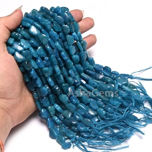 May include: A strand of blue apatite gemstone beads, each bead is a unique, irregular shape. The beads are strung on a thread and have a tassel at the end.