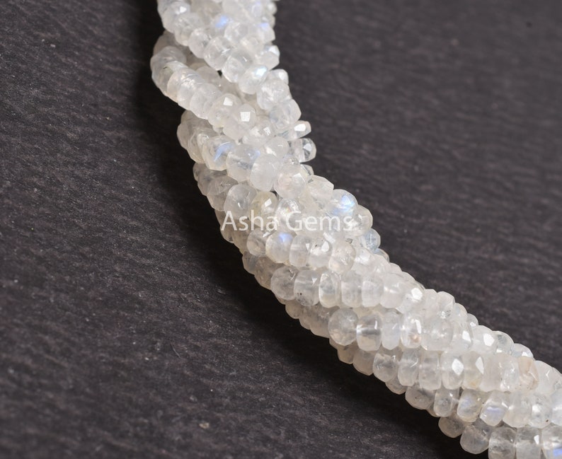 May include: A strand of white moonstone beads, each bead is faceted and has a slightly iridescent sheen. The beads are strung together in a continuous strand, and the strand is twisted into a spiral shape. The beads are approximately 4mm in diameter.