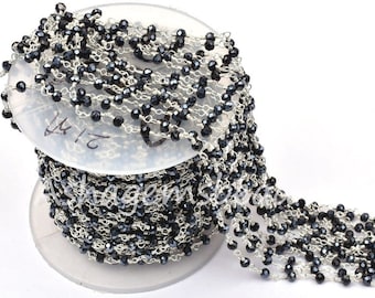 May include: A silver chain with black faceted beads. The chain is wound around a spool. The chain is 18 inches long.