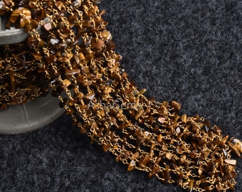 May include: A gold chain with brown tiger's eye gemstone beads. The chain is made of small, linked pieces of metal and is strung with irregular shaped beads.