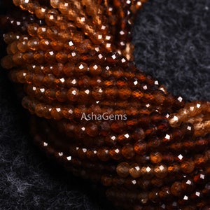 May include: A strand of brown faceted gemstone beads. The beads are small and round, and they have a shiny, polished finish.