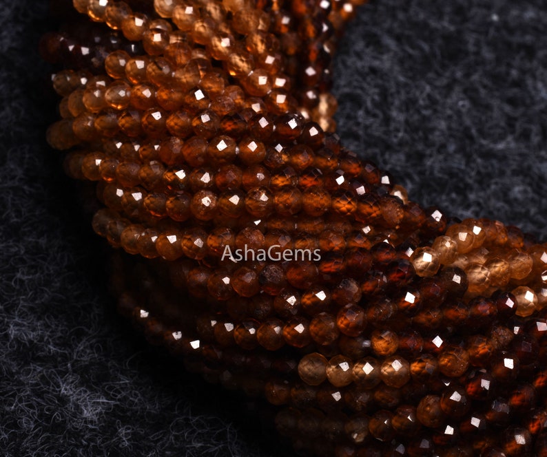 May include: A strand of brown faceted gemstone beads. The beads are small and round, and they have a shiny, polished finish.
