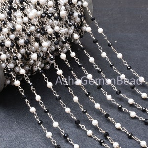 Könnte beinhalten: Eine Spule mit silberner Kette mit schwarzen und weißen Perlen. Die Kette besteht aus kleinen, runden Perlen und ist perfekt für die Herstellung von Schmuck.