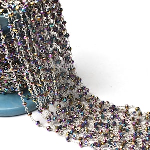 May include: A silver chain with iridescent faceted beads. The chain is wound around a blue spool.