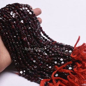 May include: A strand of dark red garnet beads, approximately 4mm in size, with a tassel at the end. The beads are faceted and have a smooth, polished finish. The strand is approximately 18 inches long.