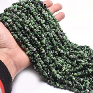 Peut inclure: Un brin de pierres précieuses en forme de copeaux de couleur verte, noire et rose. Les copeaux sont de forme irrégulière et ont une texture brute et naturelle. Le brin mesure environ 46 cm de long.