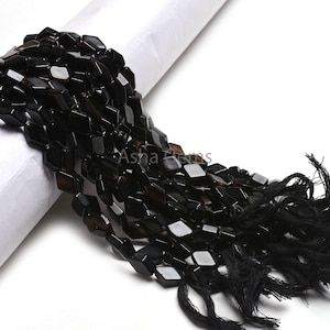 May include: A strand of black faceted gemstone beads with a black tassel. The beads are approximately 10mm in size and have a slightly irregular shape.