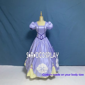 May include: A purple satin ball gown with a white flower design and pearl accents. The dress has a fitted bodice and a full skirt. The dress is on a mannequin and has the text "SORODCOSPLAY" and "Custom made on your body sizes" on the bottom.