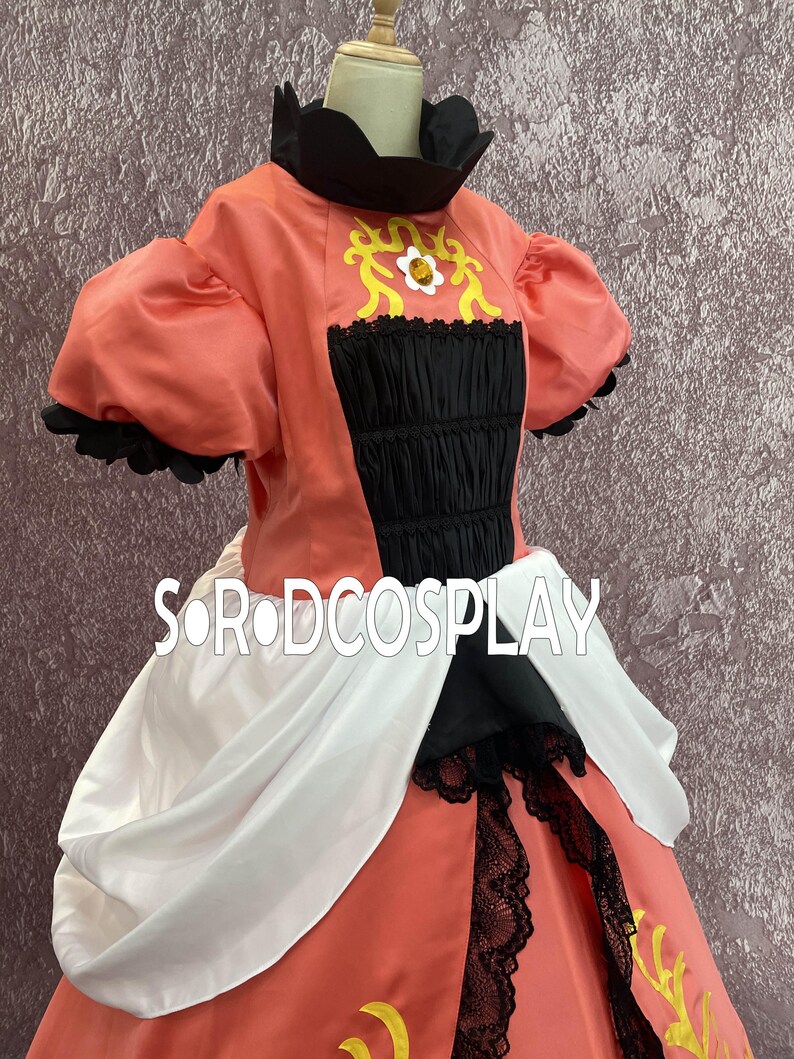 May include: A coral-colored costume dress with black and white accents. The bodice features a black, ruched panel and a high, black collar. Gold and white floral designs adorn the bodice. The skirt has black lace trim and a white drape.