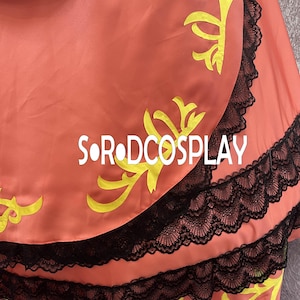 May include: A coral-colored fabric with yellow floral designs and black lace trim. The text "SOR DCOSPLAY" is printed in white across the fabric. The fabric appears to be part of a costume or garment.