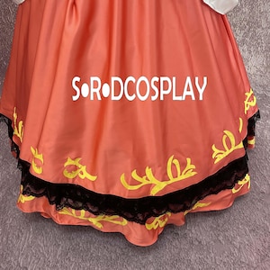 May include: A close-up of a coral-colored garment with the text "S&bull;R&bull;DCOSPLAY" in white. The garment has yellow decorative elements and a black lace trim along the bottom edge. The fabric is gathered and flowing.