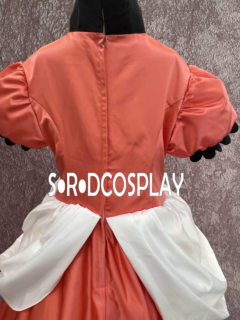 May include: A cosplay costume featuring a coral-colored bodice with short, puffed sleeves trimmed in black. The costume includes a white skirt and the text "S&bull;R&bull;DCOSPLAY". The back of the costume is visible, showing a zipper closure.