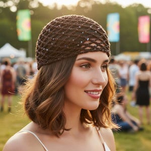 May include: A brown crocheted head covering with a net-like design and scattered sequins. The head covering is worn by a person with brown hair and a white top. The background shows a crowd of people and colorful banners.