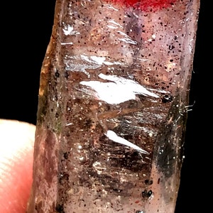 以下が含まれることがあります： 赤と紫のインクルージョンを持つ透明な水晶。クリスタルは先端が尖っており、粗い自然な質感です。