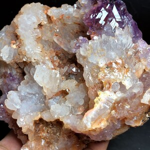 Puede incluir: Un cúmulo de cristales de amatista incrustados en una matriz de cuarzo blanco y marrón. Los cristales de amatista son de color púrpura intenso y tienen un brillo vítreo. Los cristales de cuarzo son transparentes y tienen un color blanco lechoso.