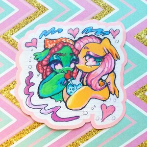 Puede incluir: Una pegatina con dos personajes de dibujos animados, uno verde y otro rosa, con corazones y líneas onduladas a su alrededor. El personaje verde sostiene una pipa de vidrio con humo saliendo de ella. La pegatina tiene un fondo rosa con líneas blancas.