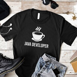 May include: Black t-shirt with a white coffee cup and the text "JAVA DEVELOPER" on a white wooden background.