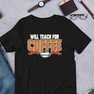 以下が含まれることがあります： オレンジと茶色の文字で「WILL TEACH FOR COFFEE」と書かれた黒いTシャツ。テキストの下には、蒸気が出ている漫画のコーヒーカップがあります。