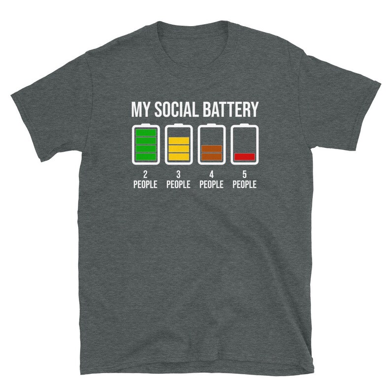 May include: A dark gray t-shirt with the text "MY SOCIAL BATTERY" and a graphic of five battery icons. The battery icons are labeled with numbers 2 through 5 and the text "PEOPLE". The first battery icon is green, the second is yellow, the third is brown, and the fourth is red.