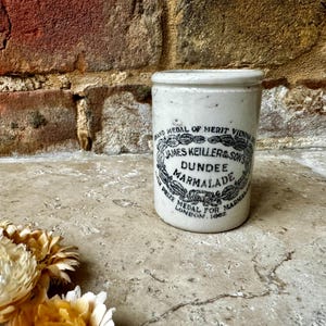 May include: White ceramic jar with a black and white label that reads "MIND MEDAL OF MERIT VIENNA JAMES KEILLER & SON'S DUNDEE MARMALADE PRIZE MEDAL FOR MARMALADE LONDON 1862".