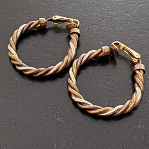 Orecchini a clip vintage Avon Hoop. Orecchini a cerchio intrecciati in metallo misto firmati Avon. Classici orecchini a cerchio con corda intrecciata.