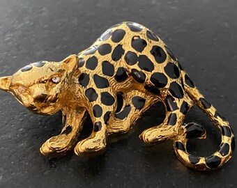 May include: Gold-toned brooch shaped like a leopard with black enamel spots. The leopard has a rhinestone in each eye.