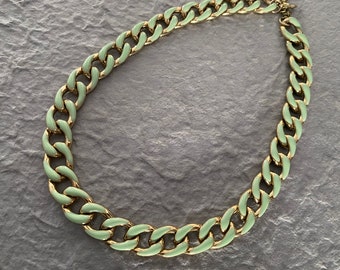 May include: A gold chain necklace with a light green enamel finish. The chain is thick and has a chunky link design.