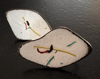 May include: Two white ceramic earrings with abstract designs in yellow, red, black, and blue.