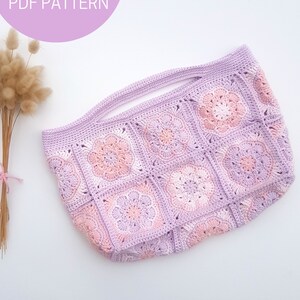 May include: A crocheted tote bag with a pink and purple floral design. The bag has a wide, flat base and two handles. The bag is made with a granny square stitch.