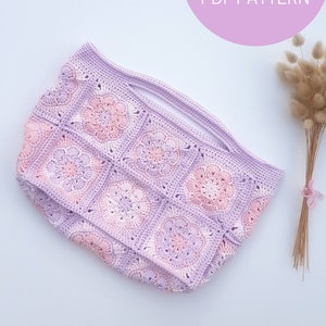 May include: A crochet bag with a pink and purple color scheme. The bag is made of granny squares with a flower design. The bag has a wide opening and a handle.
